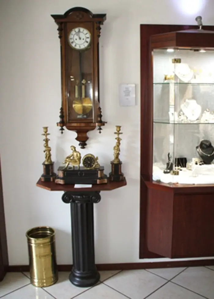 Wanduhr aus Holz wird im Verkaufsraum neben einerSchmuckvitrine ausgestellt.